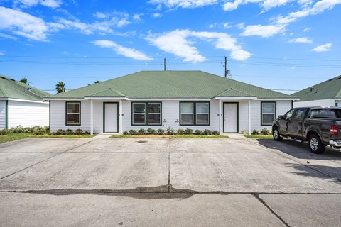 a white house with a gray roof and a black truck parked in front of it